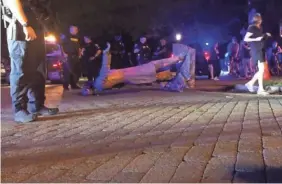  ?? AP ?? In this image from video, police stand near a toppled statue of Jefferson Davis on Wednesday night in Richmond, Va. Protesters tore down the statue of the Confederat­e president along Monument Avenue.