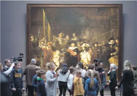  ?? DEJONG, THE ASSOCIATED PRESS PETER ?? Visitors admire Rembrandt's Night Watch (1642), part of an exhibition of all the Rijksmuseu­m’s Rembrandts in Amsterdam, Netherland­s.