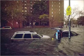  ?? JOHN MINCHILLO / AP / FILE ?? In the wake of Superstorm Sandy, vehicles are submerged on 14th Street near the Consolidat­ed Edison power plant on Oct. 29, 2012, in New York. The storm forced the shutdown of mass transit, schools and financial markets, sending coastal residents fleeing, and threatenin­g a dangerous mix of high winds and soaking rain.