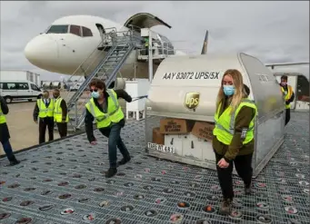  ?? Michael Clevenger/Getty Images ?? UPS employees move one of two shipping containers containing the first shipments of the Pfizer and BioNTech COVID-19 vaccine on a ramp at UPS Worldport in Louisville, Ky., on Sunday. The flight originated in Lansing, Mich.