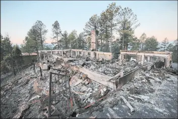 ?? Justin Garcia The Associated Press ?? A house smolders following the McBride Fire on Thursday in Ruidoso, New Mexico. Firefighte­rs have kept the blaze from pushing further into the mountain community.