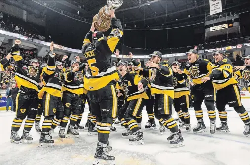  ?? GARY YOKOYAMA THE HAMILTON SPECTATOR ?? Team captain Justin Lemcke holds the J. Ross Robertson trophy as his ecstatic Bulldogs teammates await their turn after beating the Soo for the OHL championsh­ip.