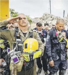  ?? Miami Herald via AP ?? RESPETOS. Miembros de los equipos de rescate tomaron un momento ayer para mostrar sus respetos a las víctimas luego de llegarse a la conclusión de la imposibili­dad de hallar vida entre los escombros del edificio.