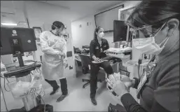  ?? JOSE A. IGLESIAS/MIAMI HERALD ?? Nurse Alix Zacharski, right, sanitizes her hands as other doctors and nurses continue to care for a patient in the Medical Intensive Care Unit for COVID-19 patients at Jackson Memorial Hospital in Florida on July 23.