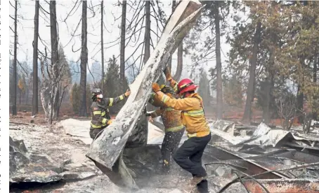  ??  ?? Picking up the pieces: Firefighte­rs moving debris while recovering human remains from a trailer home destroyed by the Camp Fire in Paradise, California. — Reuters