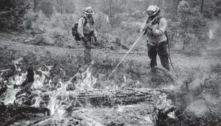  ?? Noah Berger/Associated Press ?? Firefighte­rs mop up hot spots of the Oak fire in the Jerseydale community of California’s Mariposa County. More than 3,000 residents of the state have been ordered to evacuate.