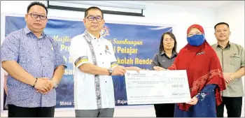  ?? ?? Ongkili presenting a mock cheque to one of the 74 school representa­tives in Kota Marudu on Friday.