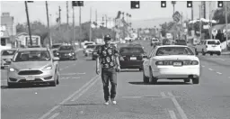  ?? MICHAEL CHOW/THE REPUBLIC ?? A pedestrian walks in the center lane while crossing Indian School Road west of 19th Avenue in Phoenix on March 10, 2019.