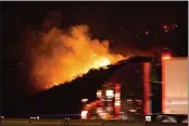  ?? RINGO H.W. CHIU — THE ASSOCIATED PRESS ?? A vehicle passes by the burning Route fire, a brush wildfire off Interstate 5north of Castaic Saturday. The wildfire near Castaic Saturday has led to the closure of a part of the major freeway in Southern California, officials told local media.