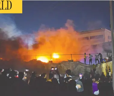  ?? ASAAD NIAZI / AFP VIA GETTY IMAGES ?? Onlookers watch and record as a massive fire engulfs the coronaviru­s isolation ward of Al-Hussein hospital in the southern Iraqi city of Nassiriya Monday evening. The fire was sparked by faulty wiring that ignited an oxygen tank.