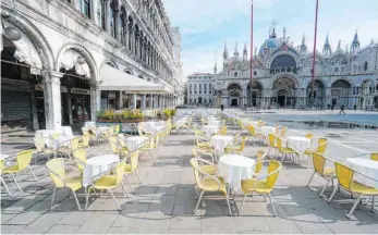  ?? FOTO: ANTEO MARINONI/DPA ?? Leere Stühle und Tische stehen vor einem Restaurant auf dem Markusplat­z in Venedig: Die Stadt sucht nach einem Weg zurück in die Normalität – womöglich ohne Massentour­ismus.