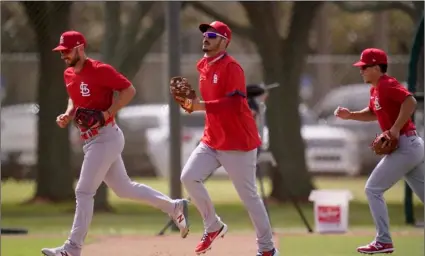  ?? AP Photo/Jeff Roberson ?? St. Louis Cardinals infielder Nolan Arenado (center) jogs out to the field with teammates Paul DeJong (left) and Tommy Edman during spring training baseball practice on Monday in Jupiter, Fla.