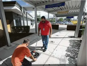  ?? Yi-Chin Lee / Staff photograph­er ?? KIPP Texas Connect workers Ajaz Ahmed, left, and David Rivera measure and paint school logos as social distancing markers on Thursday in Houston.