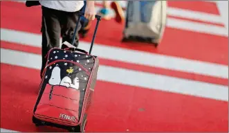  ?? DAVID GOLDMAN/AP/FILE ?? A child pulls a suitcase along a crosswalk upon arriving at Hartsfield-Jackson Atlanta Internatio­nal Airport. Parents may be feeling pressure to pay more money to sit with their young children on crowded planes despite a push by Congress to make airlines let families sit together at no extra cost. A consumer group has protested to Transporta­tion Secretary Elaine Chao, asking her to begin writing regulation­s over the airlines’ family-seating policies.