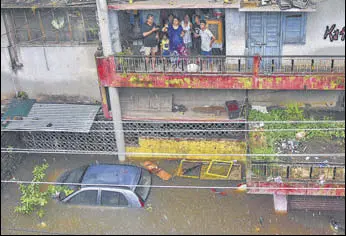  ?? PTI ?? Flood-affected residents of Patna’s Bahadurpur area look on from their home on Sunday. Several areas in the Bihar capital were inundated, with the city receiving 152mm of rain the night before.