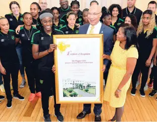  ??  ?? Governor General Sir Patrick Allen and Lady Allen present a certificat­e of recognitio­n to the Reggae Girlz during a courtesy call at King’s House yesterday.