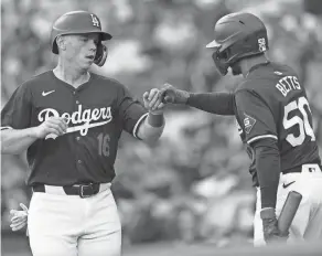  ?? KIYOSHI MIO/USA TODAY SPORTS ?? Dodgers catcher Will Smith (16) is greeted by second baseman Mookie Betts (50) after scoring a run at Dodger Stadium on Sunday. Smith has agreed to terms on a 10-year, $140 million extension, believed to be the longest term for a catcher’s contract.