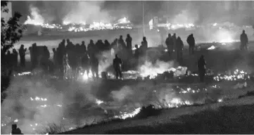  ??  ?? Migrants evacuate as a huge fire blazes through the Grande-Synthe migrant camp outside the northern French city of Dunkirk. — AFP photo