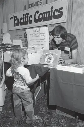  ?? Photog r aphs f rom The San Diego Union- Tribune ?? BILL LUND shows Harry Knowles, 3, future founder of Ain’t It Cool News, a book at the 1975 Comic- Con in San Diego, when the event was relaxed and casual.