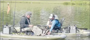  ?? Keith Bryant/The Weekly Vista ?? Ron Adams (left) steadies himself while his son, tournament director Jason Adams, helps him make some final adjustment­s on his kayak before heading out to fish in last weekend’s Fish it Forward Kayak Bass Fishing Tournament.