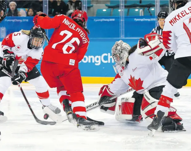  ?? LEAH HENNEL / POSTMEDIA ?? Olympic Athlete from Russia defenceman Yekaterina Nikolayeva, middle, tries to score on Canada goaltender Shannon Szabados.