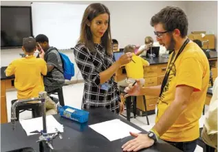  ?? STAFF PHOTOS BY C.B. SCHMELTER ?? Jill Landtroop, a new teacher coach, helps seventh-grade science teacher Owen Bogolin, right, set up an experiment Friday at Orchard Knob Middle School.