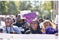  ?? (Pine Bluff Commercial/I.C. Murrell) ?? Danielle Bobo (left) and Sariah Wilson (center, foreground) lead cheers as they march through downtown Pine Bluff for the Domestic Violence Walk on Tuesday.