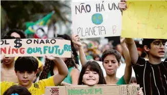  ?? Sergio Moraes - 25.ago.19/Reuters ?? Manifestan­tes carregam cartazes em marcha em defesa da Amazônia, no Rio de Janeiro; clima preocupa os mais jovens, de acordo com pesquisa