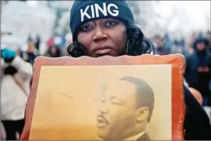  ?? JASON CONNOLLY/AFP ?? A woman holds a picture of Dr Martin Luther King Jr while marching in Denver, Colorado, during the city’s Martin Luther King Jr parade, on January 16.