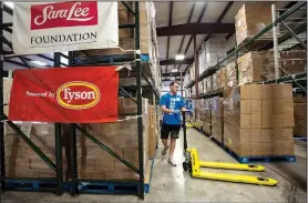  ?? NWA Democrat-Gazette/SPENCER TIREY ?? Thomas Smilie, a Wal-Mart volunteer, uses a pallet jack Wednesday at the Northwest Arkansas Food Bank to move plates of boxed food in the warehouse.