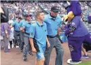  ?? DAVID ZALUBOWSKI/ASSOCIATED PRESS ?? Josh Cordova, 13, left, of Denver, heads to the field with home plate umpire Cory Blaser before the Colorado Rockies host the Los Angeles Dodgers on Sunday.