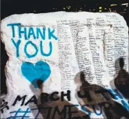  ?? Jake May / Associated Press ?? The shadows of Michigan State students appear on “the rock” on the university campus, which was painted with “Thank You” and includes the names of the women who gave victim impact statements during the Larry Nassar sexual assault sentencing hearing.