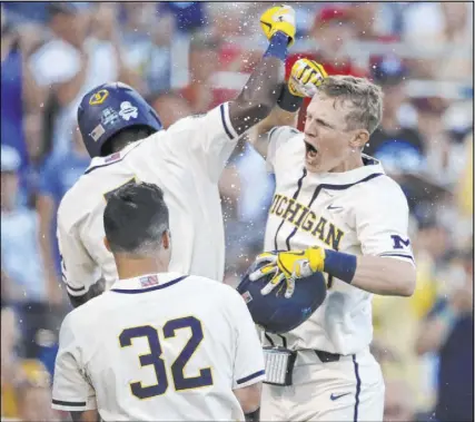  ?? Nati Harnik The Associated Press ?? Michigan first baseman Jimmy Kerr, right, the nephew of RJ Opinion page editor John Kerr, celebrates after hitting a two-run homer against Vanderbilt in Game 1 of the College World Series finals on Monday.