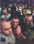  ??  ?? Khabib Nurmagomed­ov gets escorted out of the arena after defeating Conor McGregor.