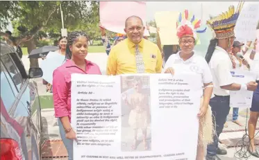  ??  ?? The boy’s mother, Karen Small (left) holds a placard showing her son in his traditiona­l wear, and quoting articles from the Convention on the Rights of the Child and Guyana’s Constituti­on, which speak to the protection of indigenous rights. (Terrence...