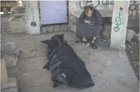  ??  ?? MOSUL: A man sits next to the body of Khadeer Hassan, who was killed during fighting between Iraqi security forces and Islamic State on the western side of Mosul. — AP