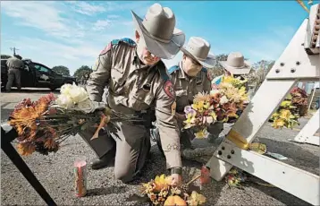  ?? SCOTT OLSON/GETTY ?? Police pick up flowers placed at a barricade Monday for victims of a shooting at a church in Sutherland Springs, Texas.