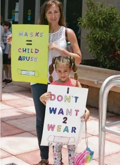  ?? EMILY MICHOT emichot@miamiheral­d.com ?? Barbara Rodas holds signs with her 6-year-old daughter, Athena Coletti, outside of the Fort Lauderdale building where the Broward School
Board was meeting on Tuesday. The board says students must wear masks when school starts next month.