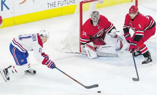  ?? BEN MCKEOWN/THE ASSOCIATED PRESS ?? Canadiens forward Brendan Gallagher tries to corral the puck in front of Hurricanes defender Noah Hanifin and goalie Cam Ward during the third period of Thursday night’s 2-0 loss in Carolina — a game in which the Habs desperatel­y needed more bodies in...