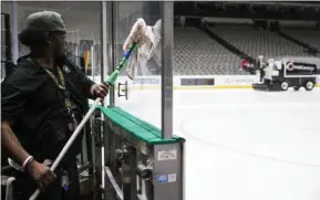  ?? ASHLEY LANDIS - THE ASSOCIATED PRESS ?? Lonnie Lockhart cleans the safety glass as the ice is resurfaced at American Airlines Arena, home of the Dallas Stars NHL hockey club, Thursday, March 12, 2020 in Dallas. The NHL announced Thursday it is suspending its season indefinite­ly in response to the coronaviru­s