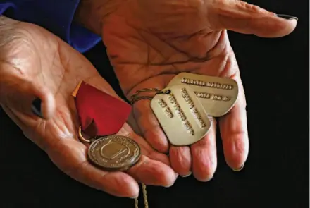  ?? Photos by Lea Suzuki/The Chronicle ?? Margie Talavera holds her dog tags and medal from her service in the Navy. She lives in the Edwin M. Lee Apartments.