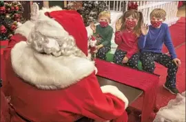  ?? Mel Melcon Los Angeles Times ?? GRIFFIN HODGE, 5, his sister Delaney, 7, and brother Wyatt, 10, sit near Santa ( Joseph Polselli) this month at the Janss Marketplac­e in Thousand Oaks.