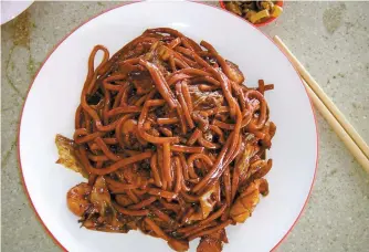  ?? John Brunton/South China Morning Post ?? A dish of Hokkien black mee, flat egg noodles in a thick black sauce with prawns, pig’s liver and crunchy pork fat, from a restaurant in Kuala Lumpur