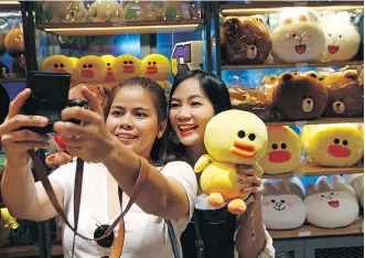  ?? SAKCHAI LALIT/ THE ASSOCIATED PRESS ?? Customers take a selfie at Line Village in Bangkok. Thailand’s most popular text-messaging service opened a retail store, and will expand to an extravagan­t digital theme park this year.