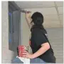  ?? (Pine Bluff Commercial/I.C. Murrell) ?? Kori Kessel, 17, of Cisne, Ill., paints the border of a window near a ceiling inside a classroom at the old First Ward School in Pine Bluff.