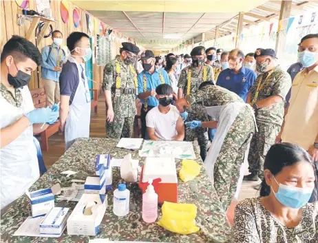  ?? — Photo by Chief Minister’s Office ?? Abang Johari (third le ) and other guests looking at a resident being vaccinated by the Combat Medic Vaccinatio­n Team at Long Singut vaccinatio­n centre.