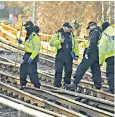  ?? ?? Police officers look for clues along the track outside Strawberry Hill station