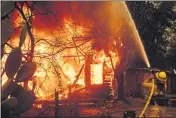  ?? NOAH BERGER — AP PHOTO, FILE ?? A firefighte­r sprays water on a burning home as the Kincade Fire burns in unincorpor­ated Sonoma County in October.