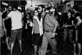  ?? DUDU GRINSHPAN/GETTY-AFP ?? A woman is escorted by a security officer Sunday after an attack in Beersheba, Israel, that left three people dead and prompted reflection in the communitie­s they left behind.