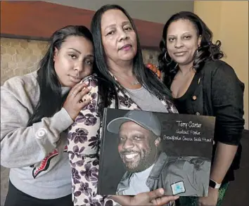  ?? Photograph­s by Genaro Molina Los Angeles Times ?? LILLIAN CARTER holds a photo book rememberin­g her husband, Terry, who was fatally hit by a truck outside a Compton burger stand in 2015. Pictured with her are daughters Crystal, left, and Nekaya Carter.